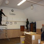 Marcus och Nils-Rune tar mått på akustikplattor  som skall monteras på gaveln, John väntar på besked.